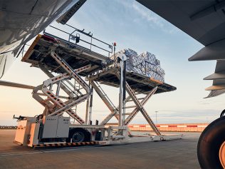 Preparation before flight. Loading of cargo containers to airplane at airport.