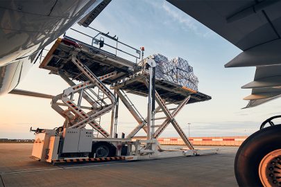 Preparation before flight. Loading of cargo containers to airplane at airport.